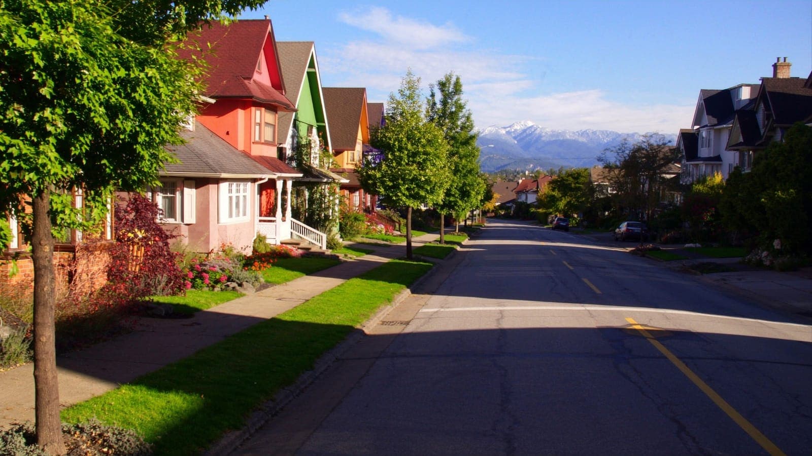 Colourful character homes on a sunny street with mountains at its end